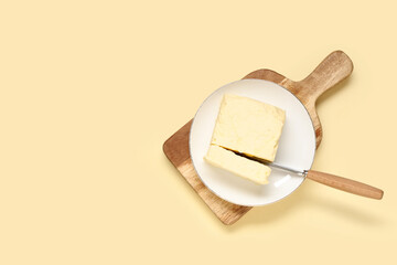 Wooden board with fresh butter and knife on color background