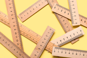 Wooden rulers on yellow background