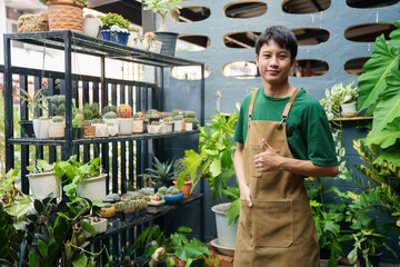 A portrait of cheerful Asian young man with gardening apron posing to camera.