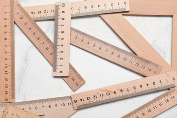 Many wooden rulers on light background, closeup