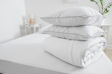 Folded blanket with pillows on bed in light room