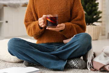 Woman holding glass cup of hot mulled wine at home, closeup
