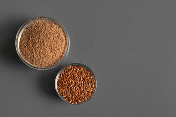 Glass bowls of flax seeds and flour on grey background