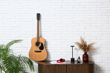 Modern acoustic guitar hanging on wall in stylish living room
