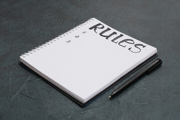 Notebook with blank list of rules and pen on dark background