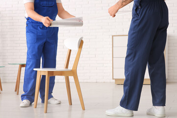 Male loaders wrapping chair with stretch film in room