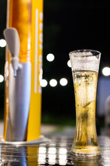 A glass of beer with beer tower on blur light gold bokeh. Relax time in restaurant.