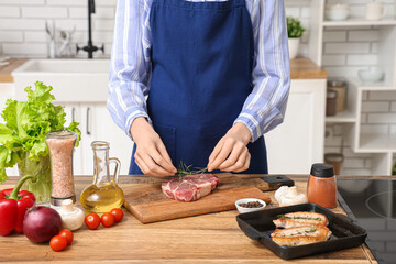 Woman cooking tasty steak in kitchen