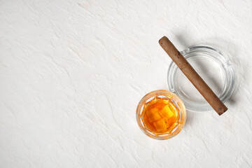 Glass of cold rum and cigar on white background