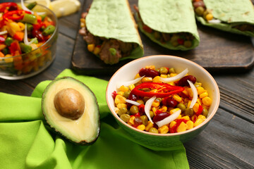 Bowl of Traditional Mexican corn salad and avocado on black wooden background, closeup. Cinco de Mayo (Fifth of May) celebration