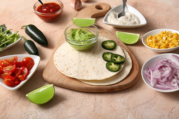 Cutting board with ingredients for tasty taco on beige grunge background