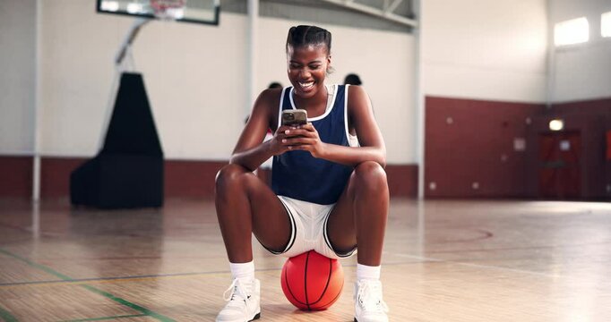 Basketball, sport and happy player with phone on court for training break, funny chat or laughing for text message. Fitness, girl and relax on ball for social media meme, workout joke or notification
