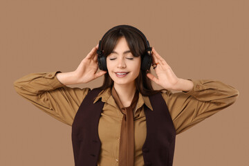 Beautiful young happy fashionable woman in headphones on brown background
