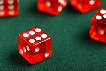 Red game dice on green background, closeup