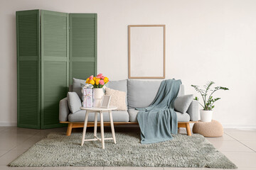 Interior of living room decorated for Mother's Day with sofa, table and blank frame