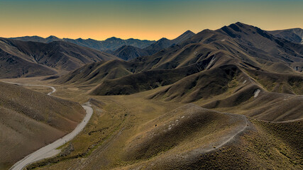 Aerial view of the alpine pass road winding its way through the arid mountain ranges at the Lindis Pass summit