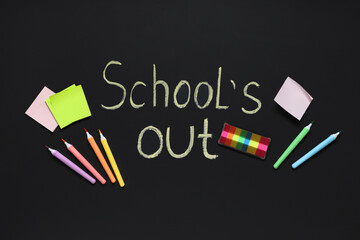 Composition with different stationery and text SCHOOL'S OUT on dark background
