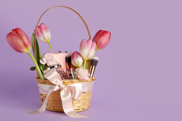 Gift basket with beautiful spring flowers, cosmetic products and makeup brushes on color background