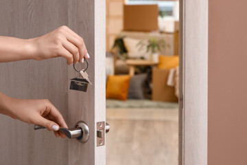 Female hands with key from her new flat opening door in room, closeup