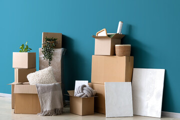 Cardboard boxes with stuff near blue wall in room on moving day