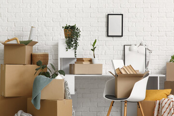 Workplace with cardboard boxes near white brick wall in room on moving day