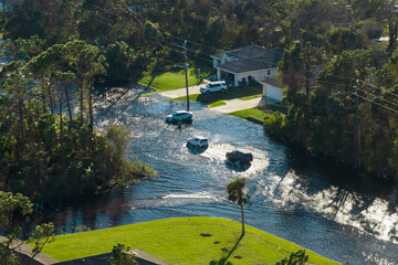 Flooded american street with moving vehicles and surrounded with water houses in Florida...