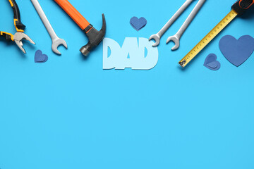 Word DAD with hearts and work tools on blue background. Father's Day celebration