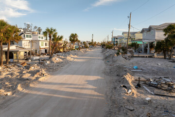 Fototapeta premium Heaps of debris rubbish on street side near severely damaged by hurricane Milton houses in Florida residential area on Manasota Key in Englewood. Consequences of natural disaster