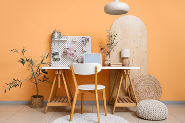 Workplace with laptop, pegboard and blossoming branches in office interior