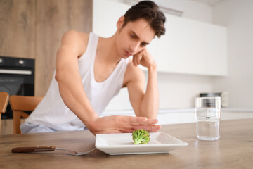 Young man with anorexia refusing from food in kitchen