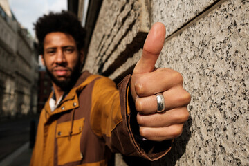 Young man showing thumb up sign in urban setting