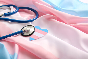 Paper heart with stethoscope on transgender flag