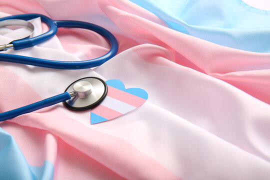 Paper heart with stethoscope on transgender flag