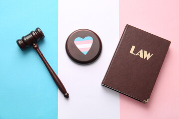 Law book with judge gavel and heart in colors of transgender flag, top view