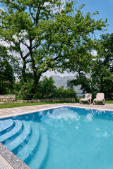 Swimming pool with steps with sun loungers in the garden overlooking the mountains