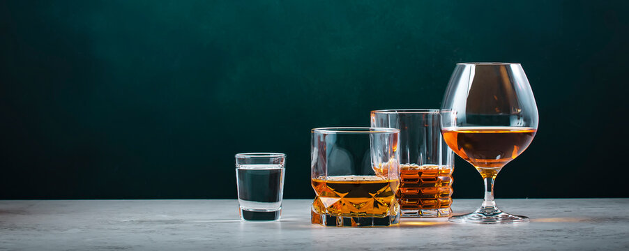 Strong hard alcoholic drinks, spirits, liqueurs, distillates, whiskey and others. Drink background banner. Alcohol set. Green wall