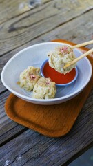 Delicious steamed dumplings with spicy dipping sauce, served in a rustic setting. Perfect for food blogs and culinary websites.