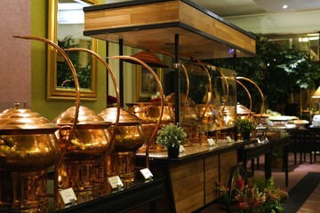 Elegant copper food warmers on a wooden cart at a lavish buffet.  Perfect for restaurant, catering, or hospitality visuals.