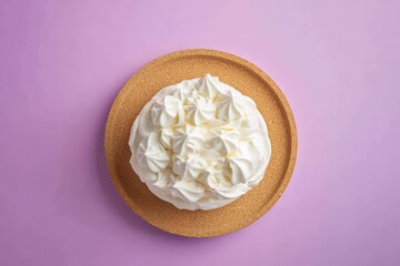 A delicate pavlova dessert with whipped meringue peaks on a cork tray.