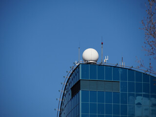 Obraz premium Modern Glass Office Building with Curved Facade Reflecting Blue Sky in Contemporary Urban Architecture