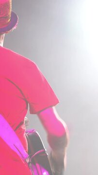 Back view of a standing drummer banging a drum on stage during a concert. Footage. Beautiful stage light, music show atmosphere.