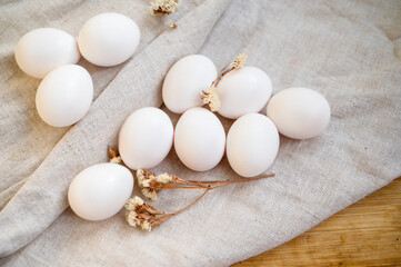 white eggs in a cardboard box, 10 pieces, on a surface made of natural materials.