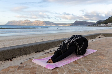 Stretching on a yoga mat at sunrise on the beach
