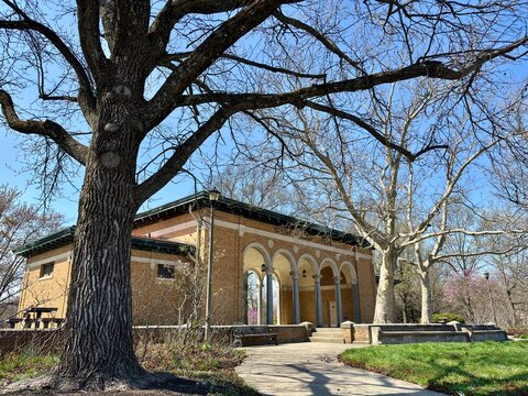 Historic brick pavilion with arched columns in early spring park