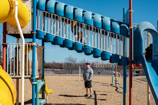 Children play on a colorful playground with dad watching