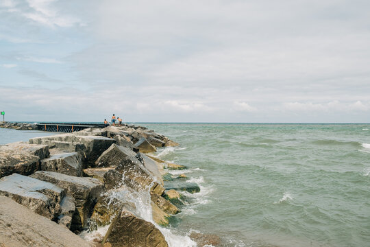 Waves crash against rocks while people enjoy a coastal walk