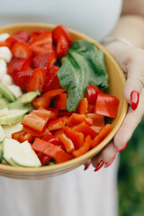 Close-up of colorful fresh salad bowl held in hand.