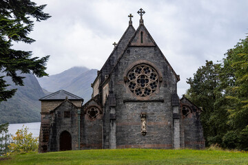 Naklejka premium St Mary and St Finnan Church rises above the shores of Loch Shiel, near the Glenfinnan Viaduct. A Gothic gem nestled in the wild landscape of the Scottish Highlands.​