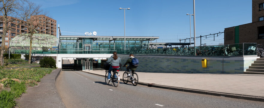 Cyclists ride under the bicycle tunnel under the railway station. On the left the Bike Apple, a bicycle parking facility in Alphen aan den Rijn, the Netherlands, April 07 2025