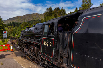 Iconic Jacobite steam train crosses Glenfinnan Viaduct and stops at the station, with historical details, smoke, and nostalgia. Timeless and magical icon in the Scottish Highlands. Locomotive interior